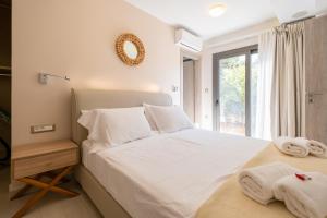 Schlafzimmer mit einem Bett mit weißer Bettwäsche und Handtüchern in der Unterkunft Glaros Casa Verde - Cozy flat with Garden near Beach in Kato Daratso