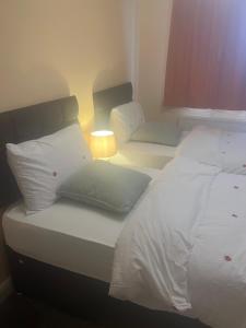 łóżko z białą pościelą i poduszkami w pokoju w obiekcie Modern 3 Bed House for 6 guests w mieście Nevendon
