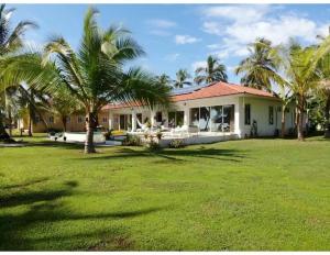 a house with palm trees in front of a yard at Casa Carey Lajas Pty Exclusive Beachfront Villa in Cabrera