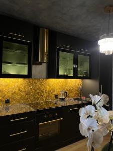 a kitchen with black cabinets and white flowers at Apartament Gwiazda Renesansu in Zamość