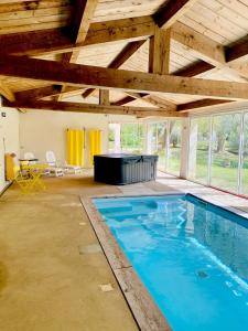 an indoor swimming pool in a building with a wooden ceiling at La Maison M 6pers in Valréas