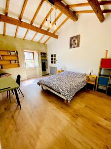 a bedroom with a bed in a room with wooden floors at La Maison M 6pers in Valréas