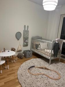 a nursery with a crib and a table and a rug at Radhus 2 våning med 5 RoK, EUROVISION in Malmö