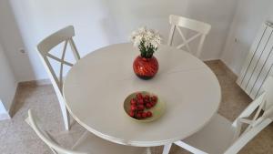 a white table with a vase of flowers and a bowl of fruit at Casa Emma in Poreč