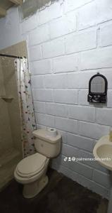 a bathroom with a toilet and a white brick wall at Cabaña Palmeras del Viento in San Bernardo del Viento
