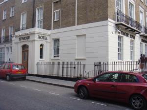 dos autos estacionados en una calle frente a un edificio en Seymour Hotel, en Londres