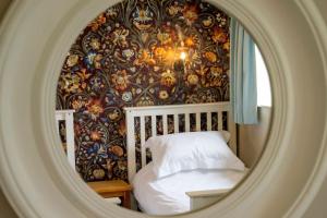 ein Schlafzimmer mit einer Tapete, einem Bett und einem Spiegel in der Unterkunft Wood Cottage in York