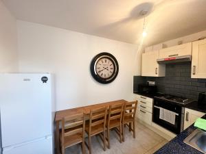 a kitchen with a table and a clock on the wall at Stay In Tooting in London