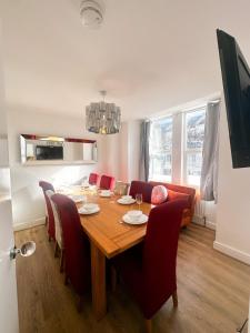 a dining room with a wooden table and red chairs at Stay In Tooting in London