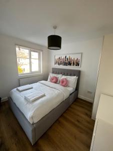 a bedroom with a bed with white sheets and pink pillows at Stay In Tooting in London