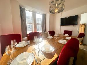 a dining room table with red chairs and a wooden table with wine glasses at Stay In Tooting in London