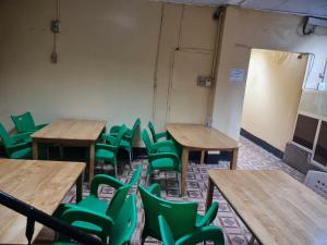 ein leeres Klassenzimmer mit Schreibtischen und grünen Stühlen in der Unterkunft Addis Guest House Djibouti in Dschibuti