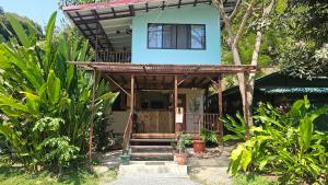 een klein huis met een veranda en een balkon bij Bamboo River House and Hotel in Dominical