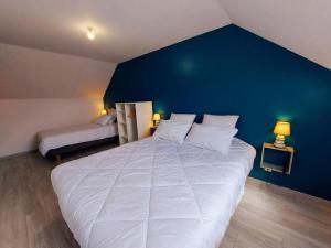 a bedroom with a large white bed and a blue wall at Gîte de la Petite Noërie - 11 personnes in Saint-Georges-le-Fléchard