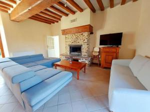 Saint-Georges-le-FléchardにあるGîte de la Petite Noërie - 11 personnesのリビングルーム(青いソファ、暖炉付)