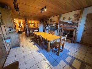 uma grande cozinha com uma mesa de madeira e cadeiras em La Fée Verte em Arc-sous-Cicon