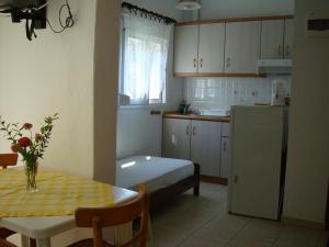 a small kitchen with a table and a refrigerator at House Maria Manolaki, 1st Floor Studios in Vourvourou
