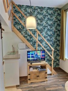 a room with a desk with a television and a staircase at Studio le petit nid douillet - Centre ville in Les Andelys