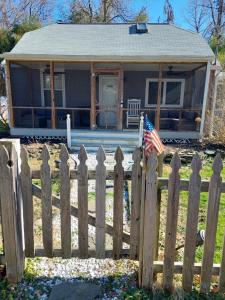 a wooden fence in front of a house with an american flag at Luxe Chesapeake Cabin * River View* Fire Pit* in Shady Side