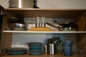 a kitchen shelf with dishes and utensils on it at Serviced Business Apartment in Lorsch