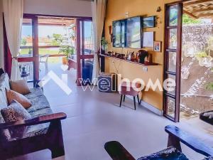 uma sala de estar com um sofá e uma televisão em Linda casa com piscina a 5 minutos da Praia em Pitimbu