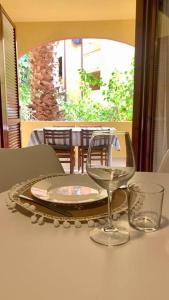 ein Tisch mit einem Teller und zwei Gläsern darauf in der Unterkunft NEST HOUSE - ESCLUSIVO APPARTAMENTO Marina di Olbia- MATER OLBIA - Beaches - close to the Airport - PRIVATE PARKING- Full comforts - in Olbia