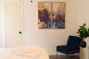a bedroom with a blue chair and a painting on the wall at H2O Haven: 5 mins To Niagara Falls in Niagara Falls