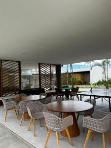ein Restaurant mit Tischen und Stühlen und eine Terrasse in der Unterkunft Makia Beach Experience Muro Alto Porto de Galinhas in Porto De Galinhas