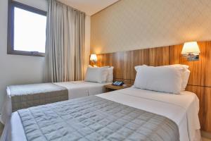 a hotel room with two beds and a window at MG Flats Hotel & Residence in Cuiabá