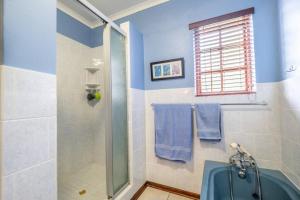 a bathroom with a shower with a blue tub at Selah-on-Sea in Kenton on Sea