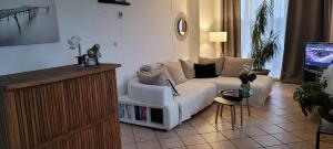 sala de estar con sofá blanco y TV en A L'orée de Soi, en Saint-Omer-en-Chaussée