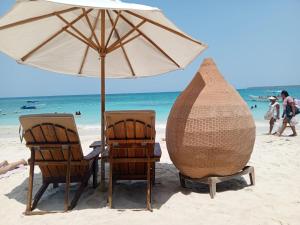 two chairs and an umbrella on the beach at Hotel Calamari Baru in Playa Blanca