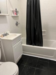 ein Bad mit einem schwarzen Duschvorhang und einem WC in der Unterkunft A bedroom with your own full bathroom next to your room in Philadelphia