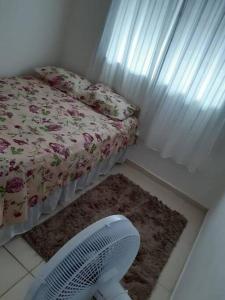 - une chambre avec un lit, un ventilateur et un tapis dans l'établissement Casa Aeroporto Maceió Palmeiras, à Maceió