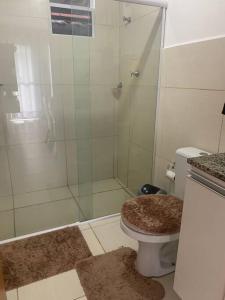 La salle de bains est pourvue d'une douche, de toilettes et d'un tapis. dans l'établissement Casa Aeroporto Maceió Palmeiras, à Maceió