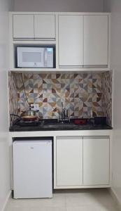 a kitchen with white cabinets and a microwave at La Bella Luna Suítes in Alto Paraíso de Goiás