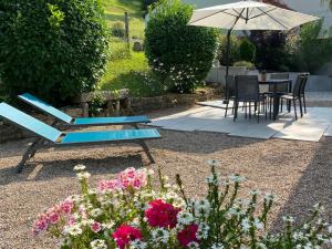 a blue bench in a garden with flowers and an umbrella at L’ Annexe in Chariez +6 photos