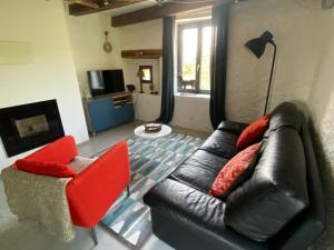 a living room with a black leather couch and a red chair at L’ Annexe in Chariez