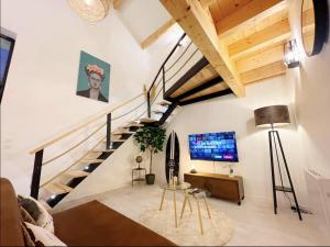 een woonkamer met een trap en een tv bij Magnifique grange rénovée au coeur de la Champagne in Les Mesneux
