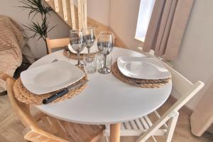 una mesa blanca con platos y copas de vino. en LaMaisonnette 500m plage Juno Beach, en Bernières-sur-Mer