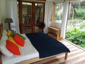 uma cama com almofadas coloridas num quarto com varanda em Infinity-house with direct access to the beach em SantʼAna