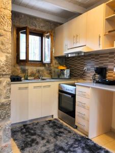 La cuisine est équipée de placards blancs et d'un four avec plaques de cuisson. dans l'établissement Delphi View!, à Galaxidi