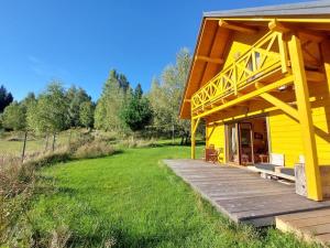 une maison jaune avec une terrasse en bois dans un champ dans l'établissement Panorama Sucha Góra ,Leśny domek, à Skawica