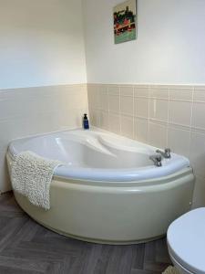 a white bath tub in a bathroom with a toilet at Annie's Hideaway in Chapel Saint Leonards