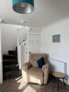 a living room with a chair and a staircase at Annie's Hideaway in Chapel Saint Leonards