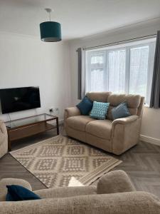 a living room with a couch and a tv at Annie's Hideaway in Chapel Saint Leonards