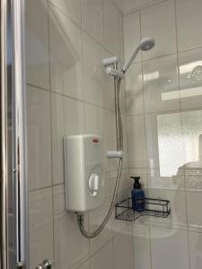 a shower in a bathroom with a white tiled wall at Annie's Hideaway in Chapel Saint Leonards