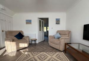 a living room with two chairs and a tv at Annie's Hideaway in Chapel Saint Leonards