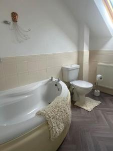 a bathroom with a white tub and a toilet at Annie's Hideaway in Chapel Saint Leonards