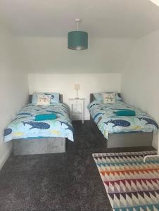 a bedroom with two beds and a table with a lamp at Annie's Hideaway in Chapel Saint Leonards